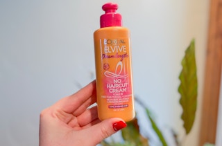 hand holding a bottle of l'oreal elvive no haircut conditioner cream