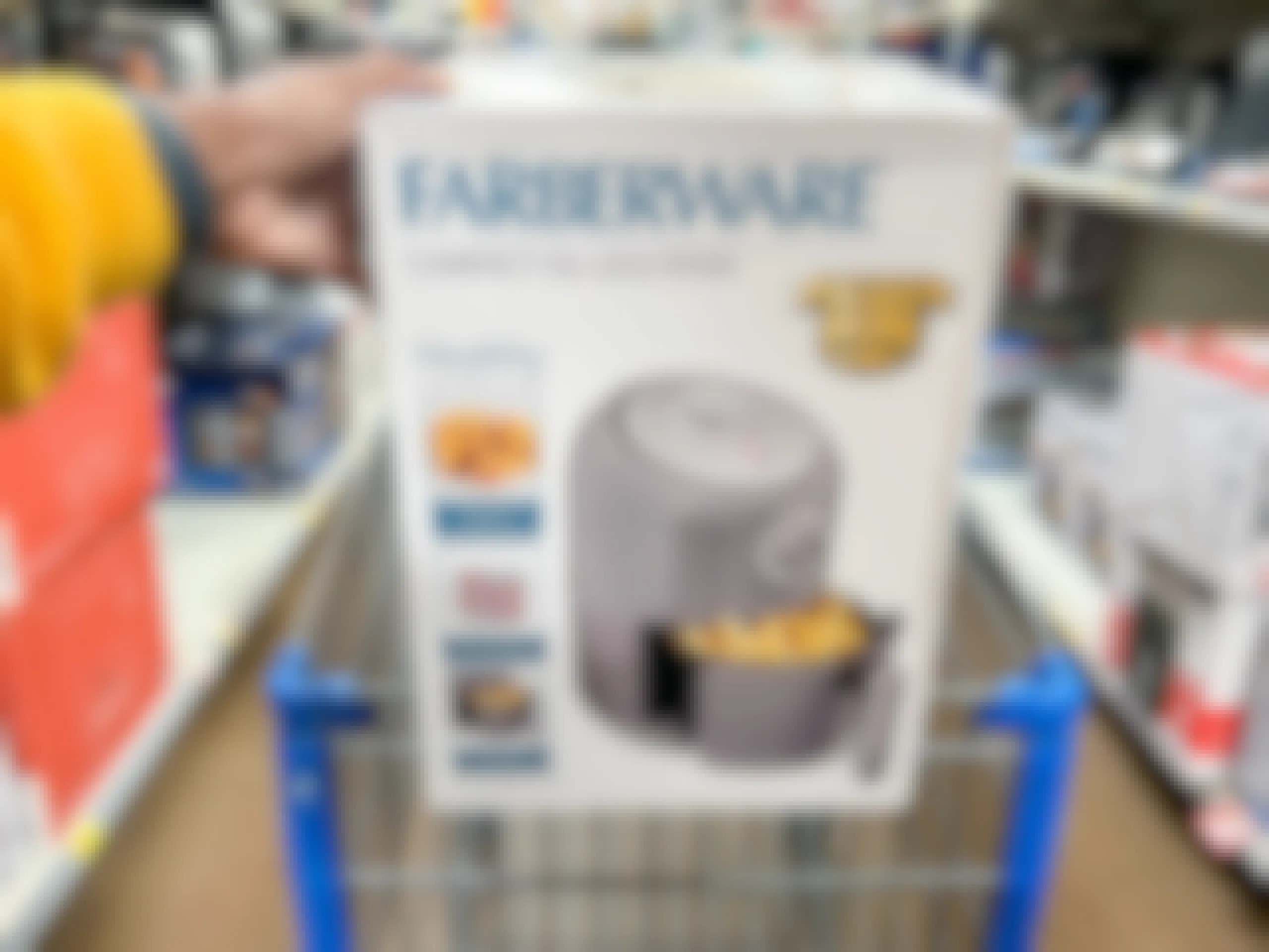 hand holding up the box of an air fryer on the edge of a Walmart shopping cart