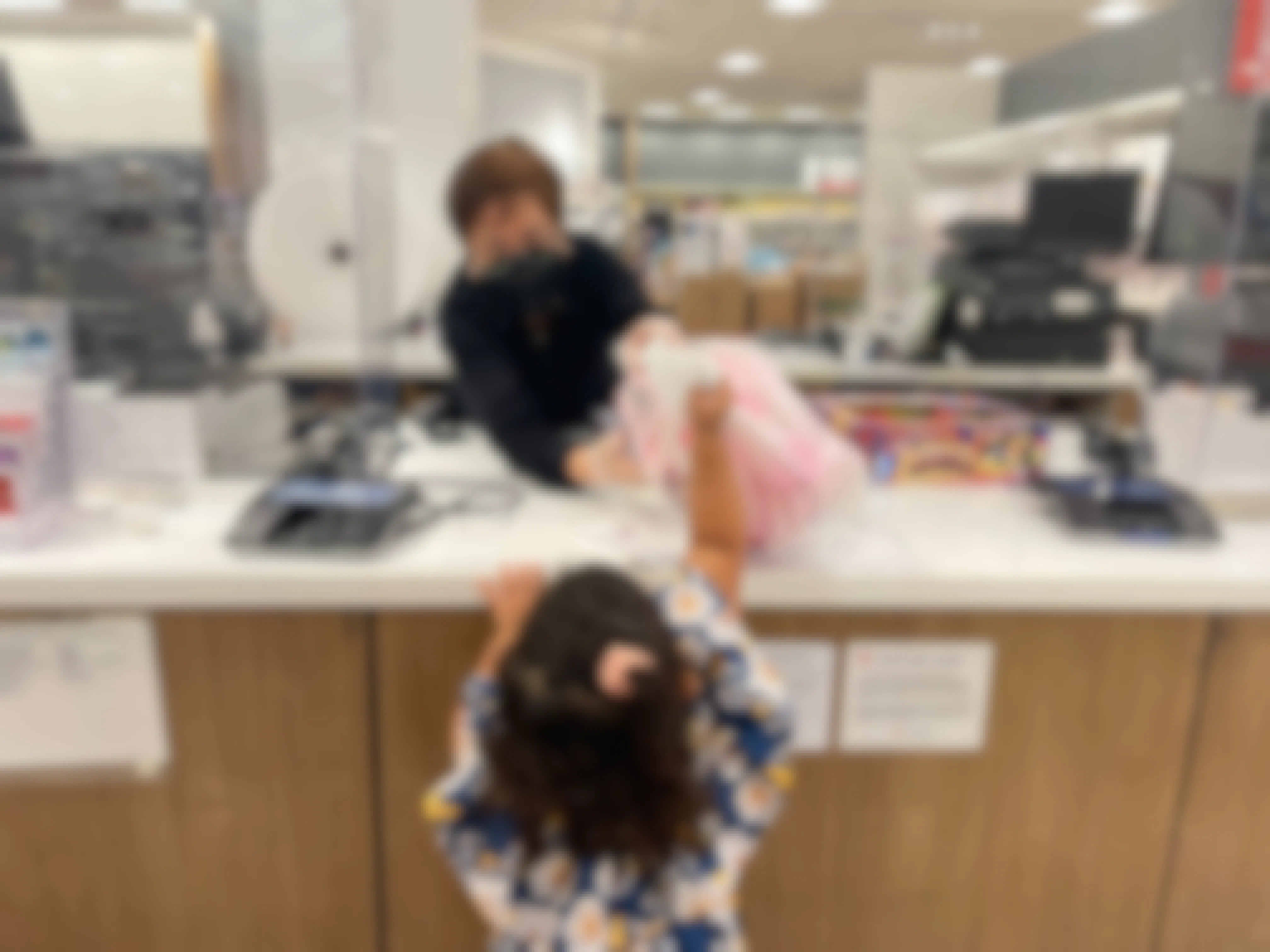 A small child taking a bag from a store cashier.
