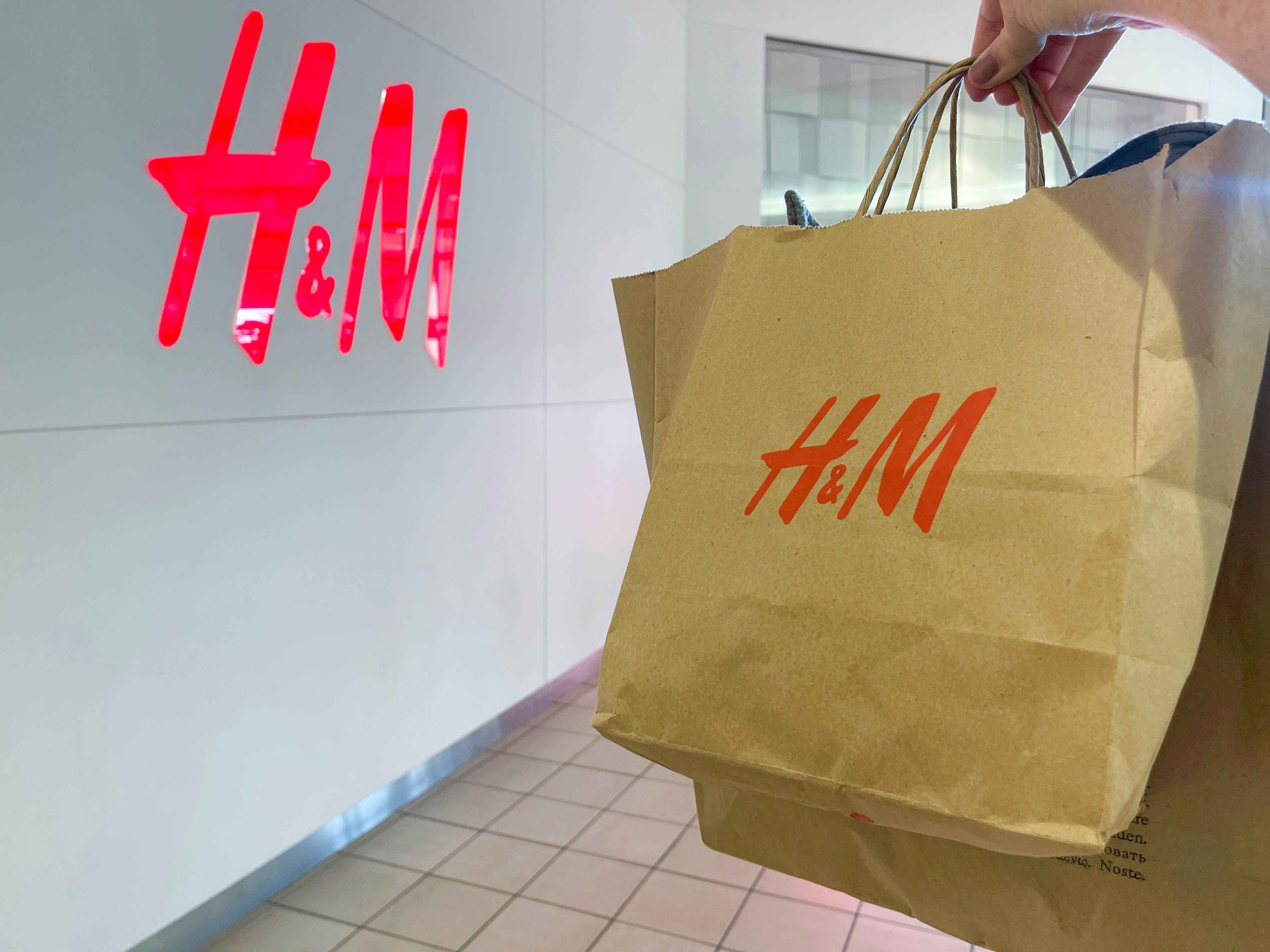a hand holding a h & M bag outside H & M store 