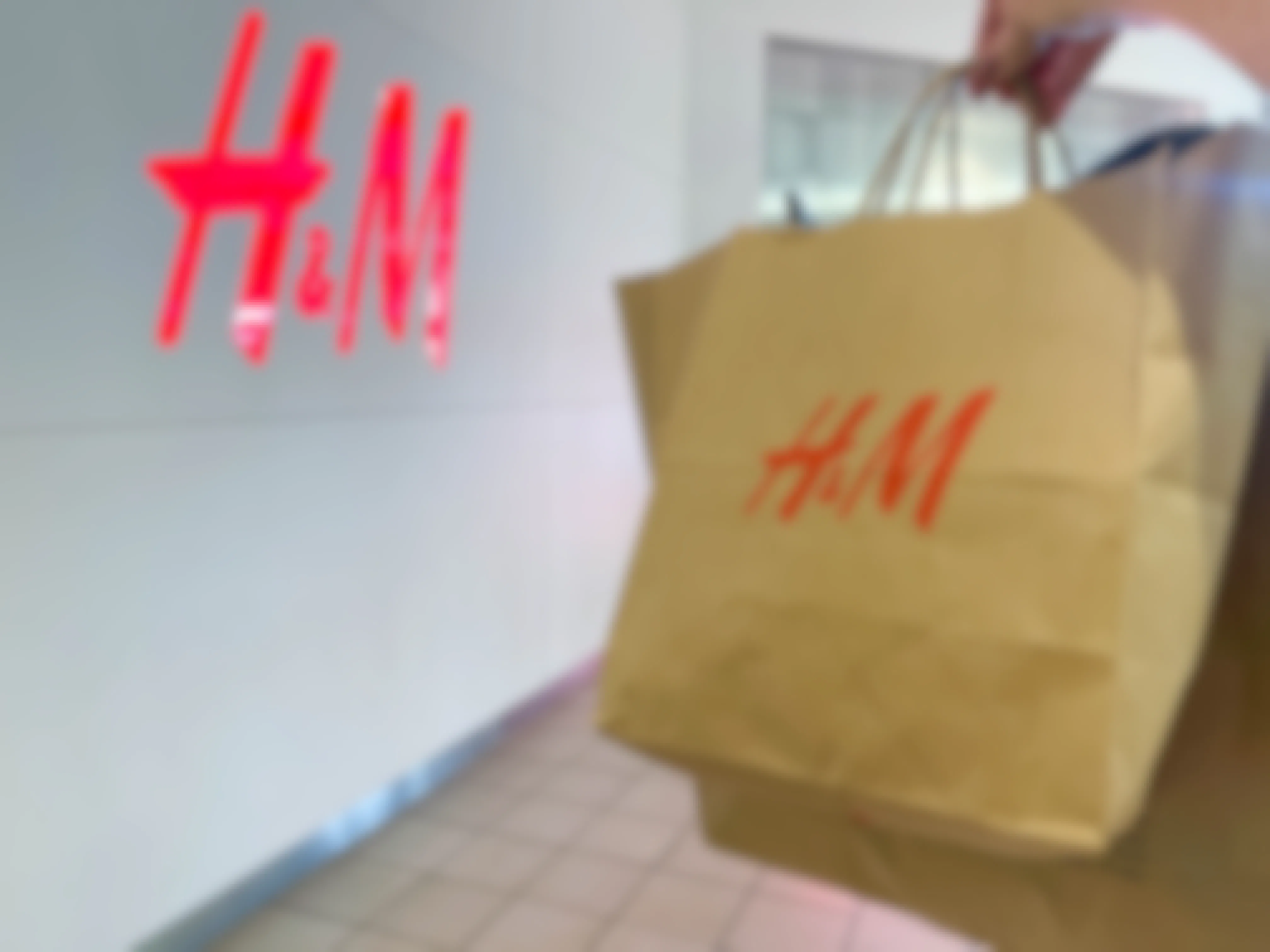 a hand holding a h & M bag outside H & M store 