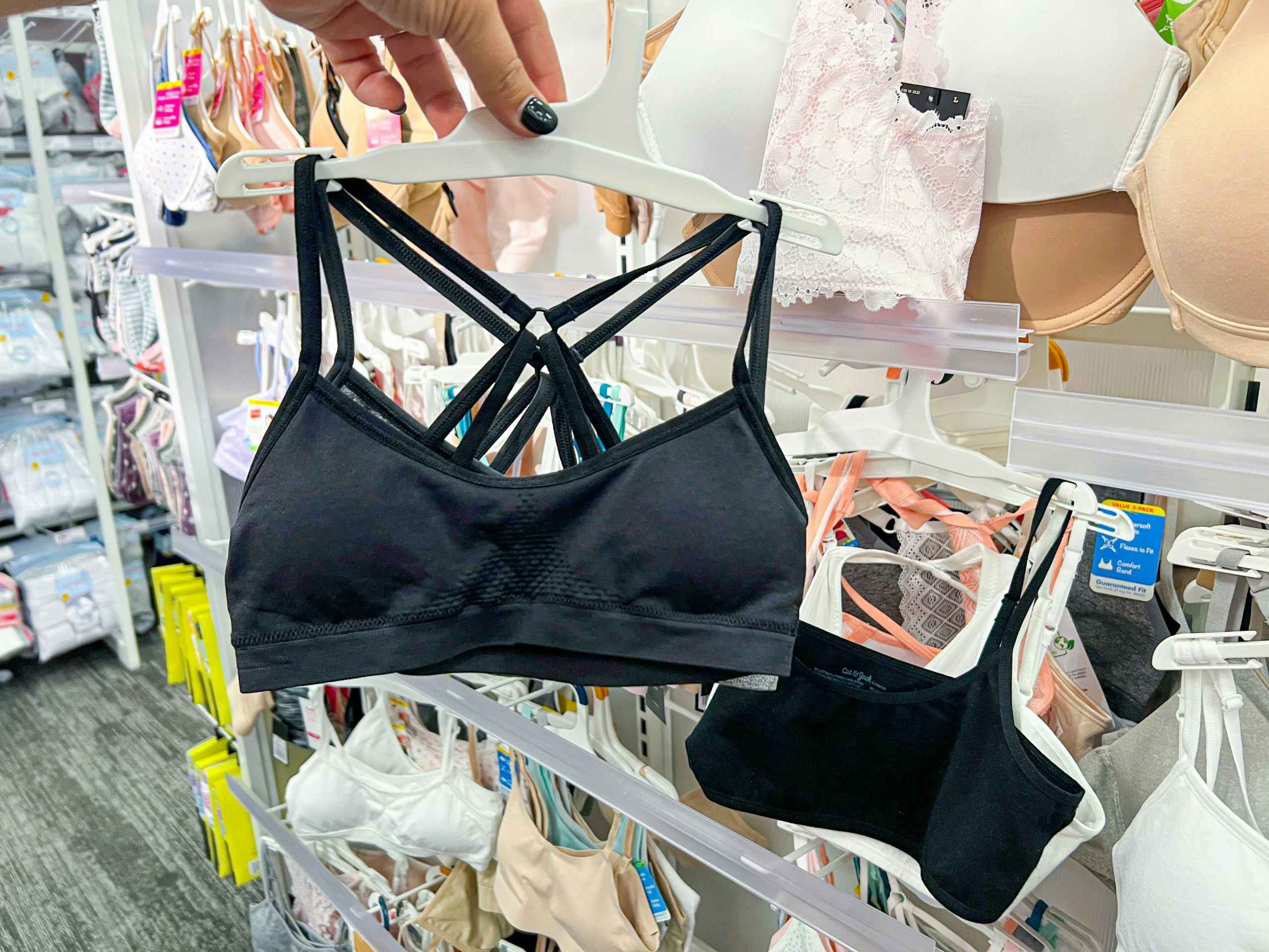 hand holding girls black bra set in front of shelf