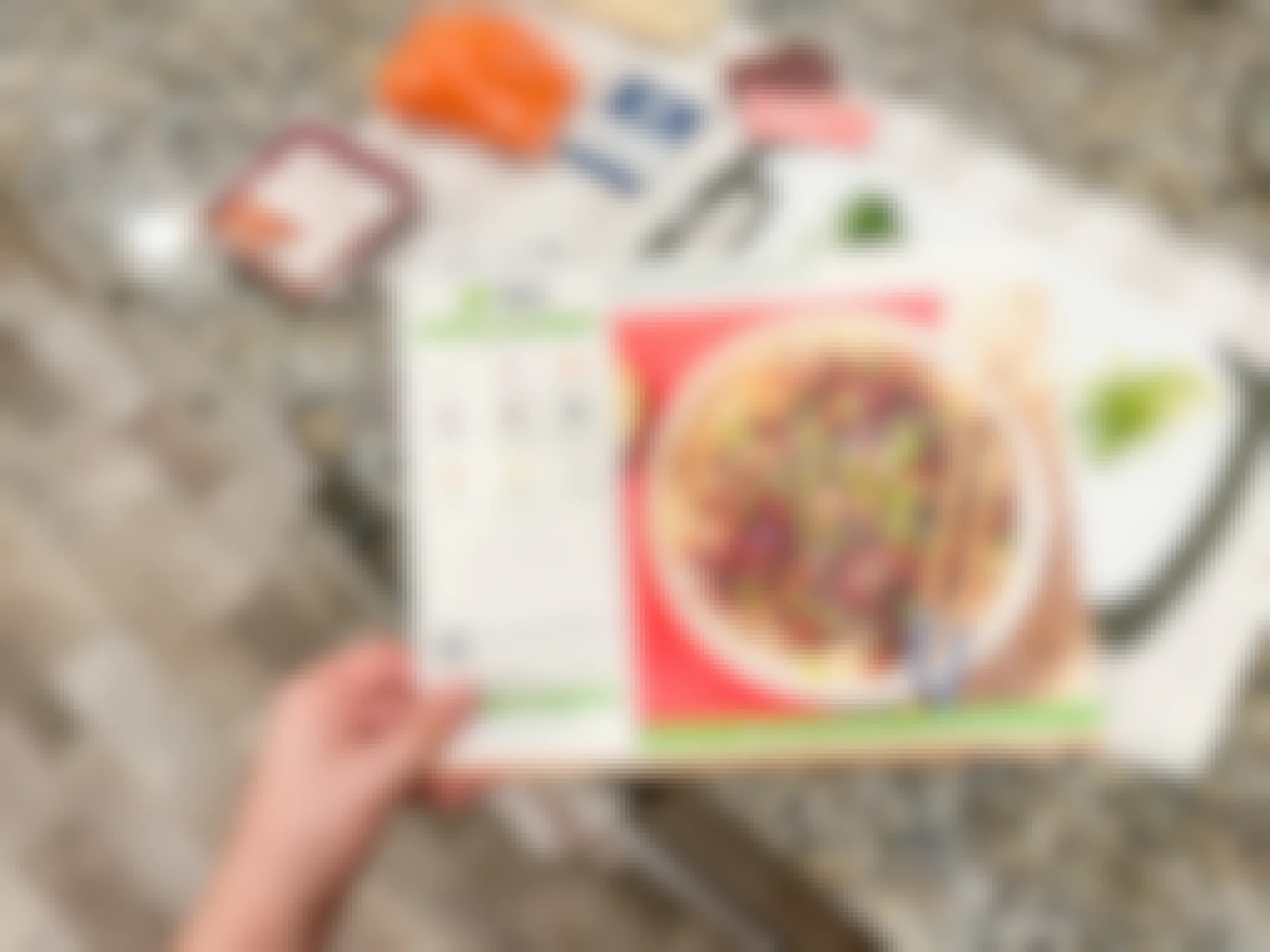 Someone holding a Hello Fresh recipe card and preparing ingredients