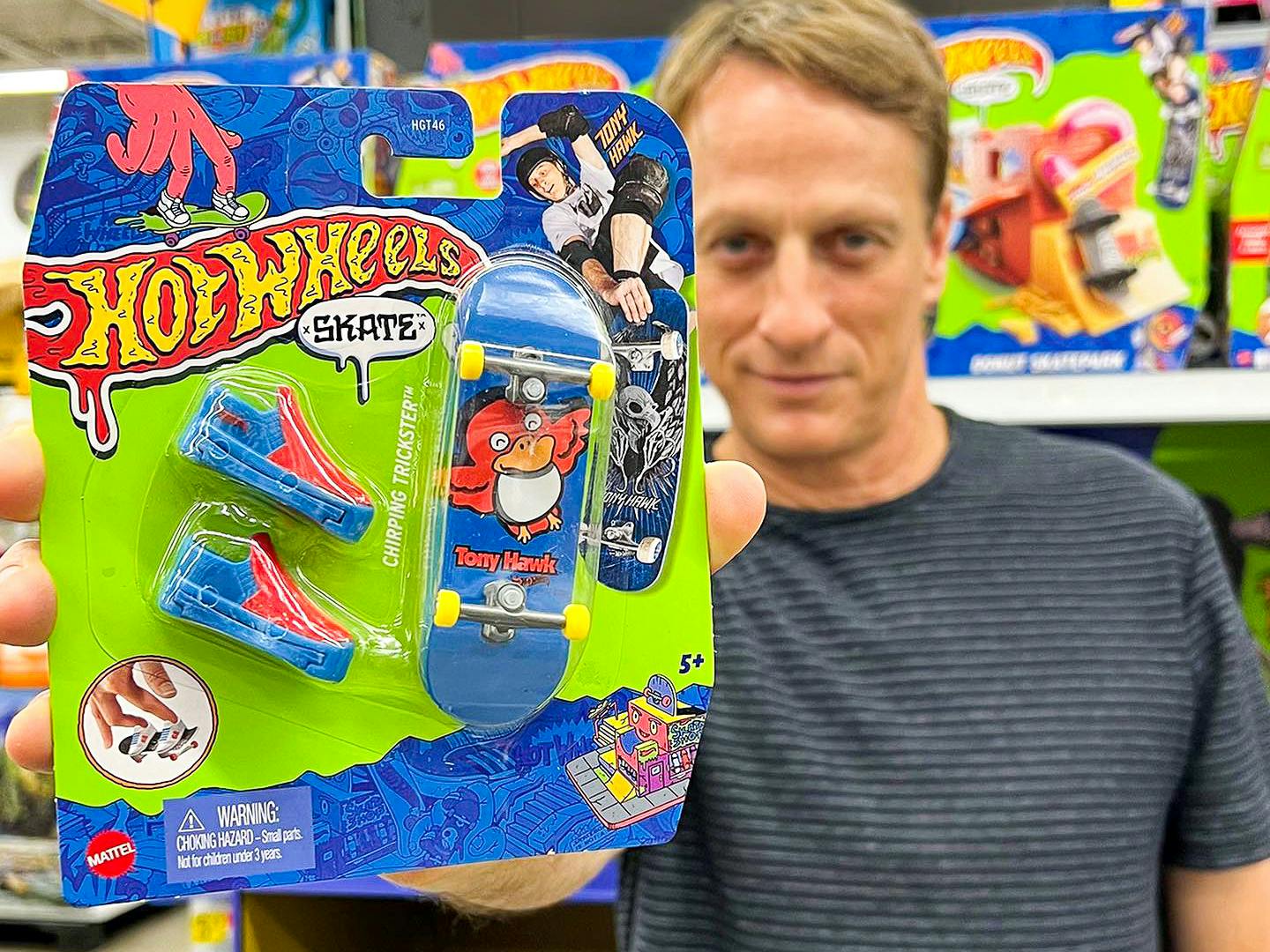 Tony Hawk in a store, holding up a Hot Wheels Chirping Trickster toy from his collab with Hot Wheels.