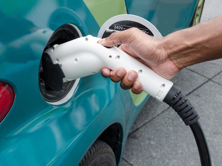 A person inserting a charger into their electric vehicle.