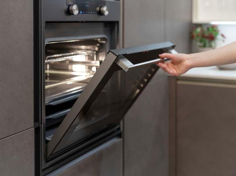 A person opening the door of their electric oven
