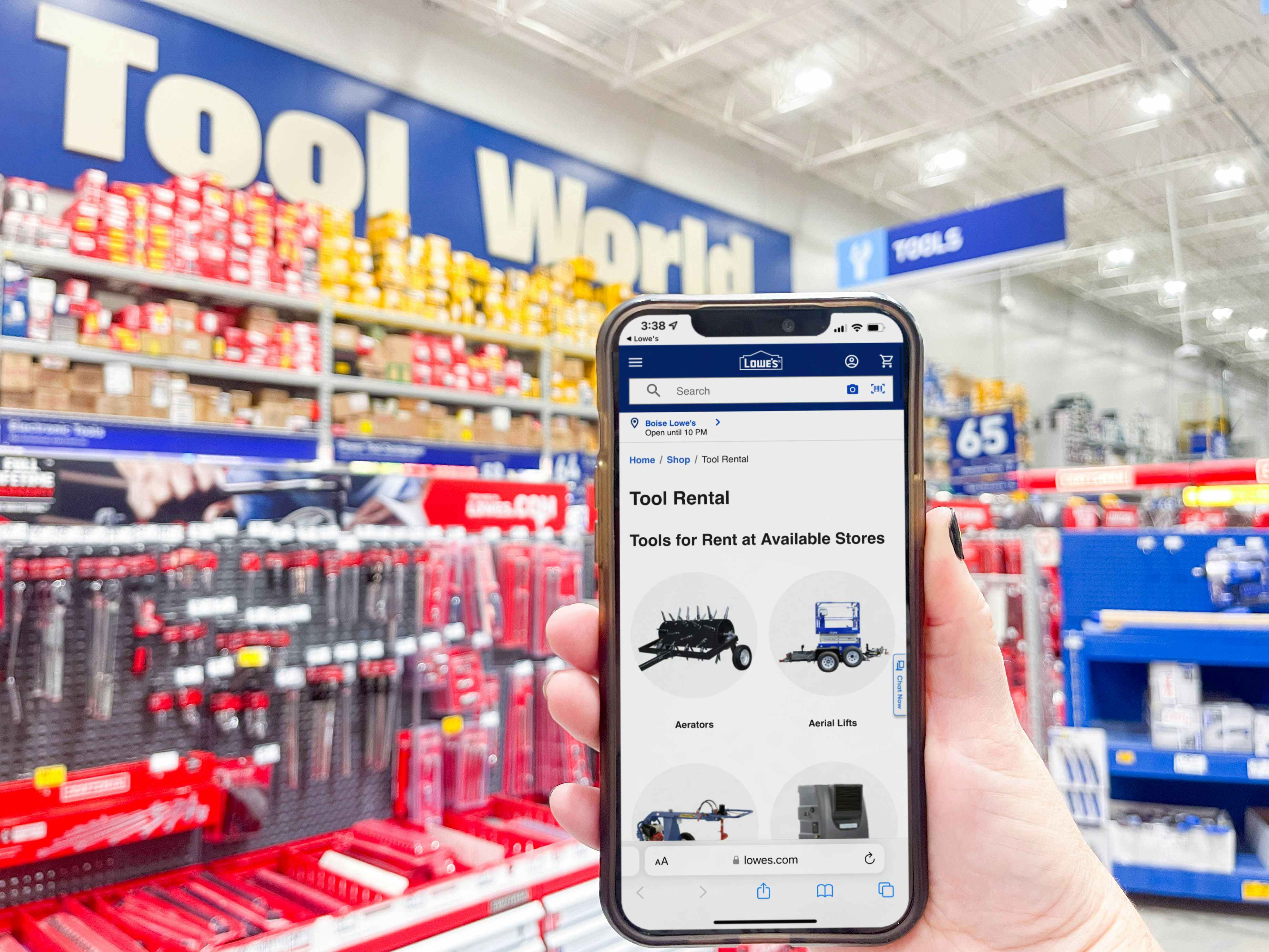 A person's hand holding a cellphone with Lowes tool rentals in tools area in store.