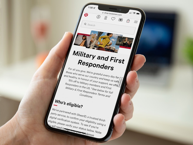 A person holding a phone displaying the information for the Lululemon military and first responders discount