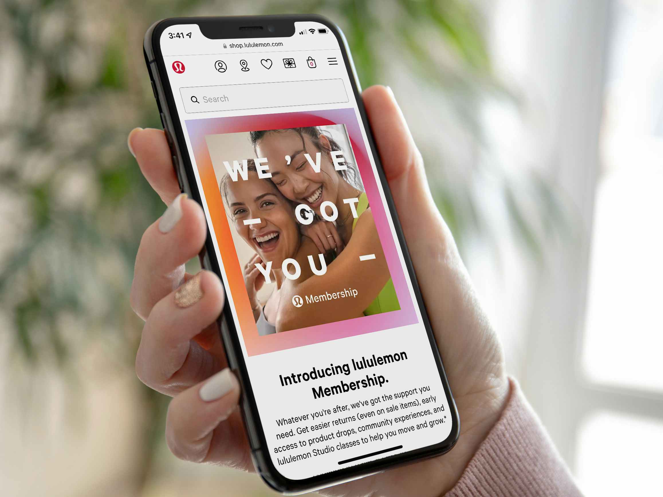 Someone holding a phone displaying the Lululemon website's page about memberships.