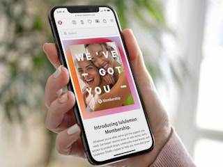 Someone holding a phone displaying the Lululemon website's page about memberships.