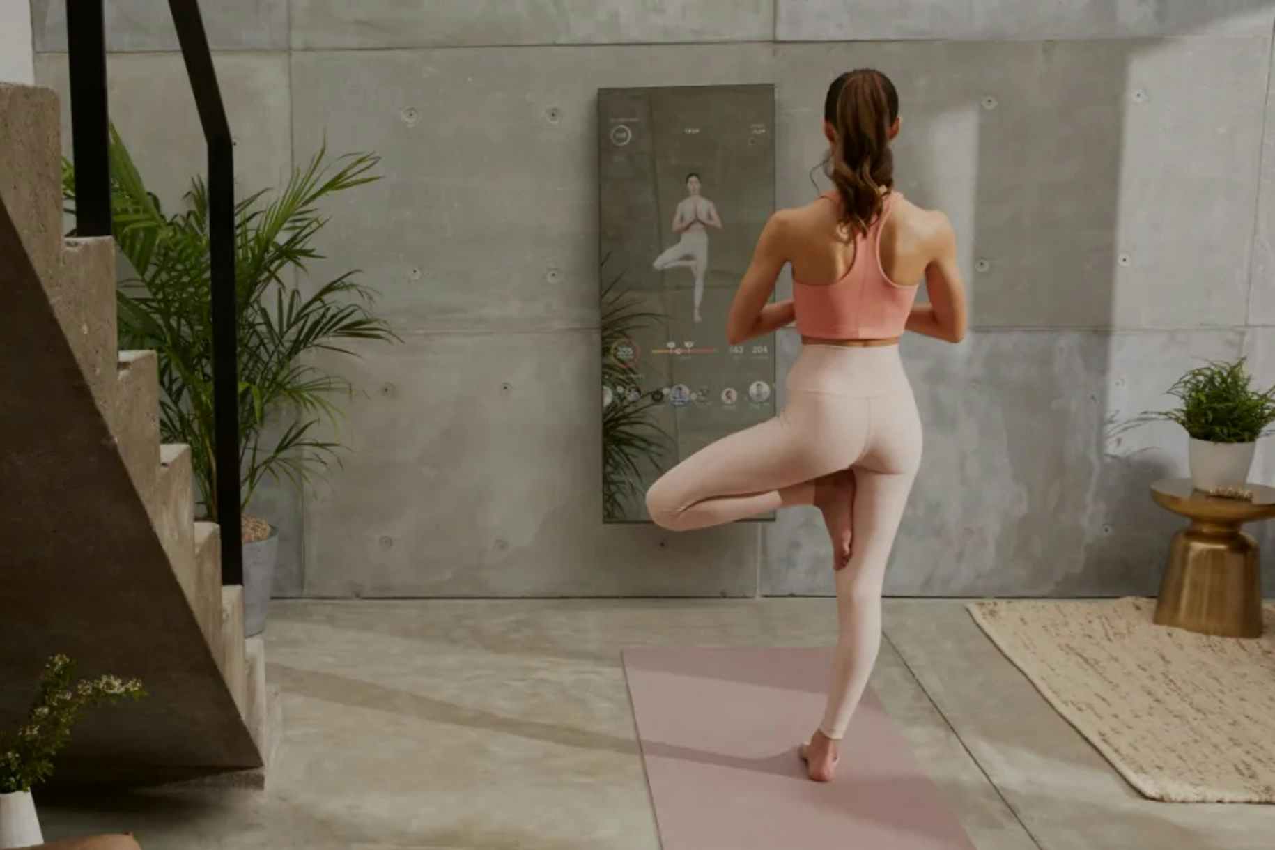 A person doing a yoga pose in front of a Lululemon studio mirror.