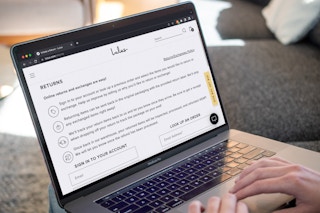 A person using a laptop looking at the Lulus return policy on their website.