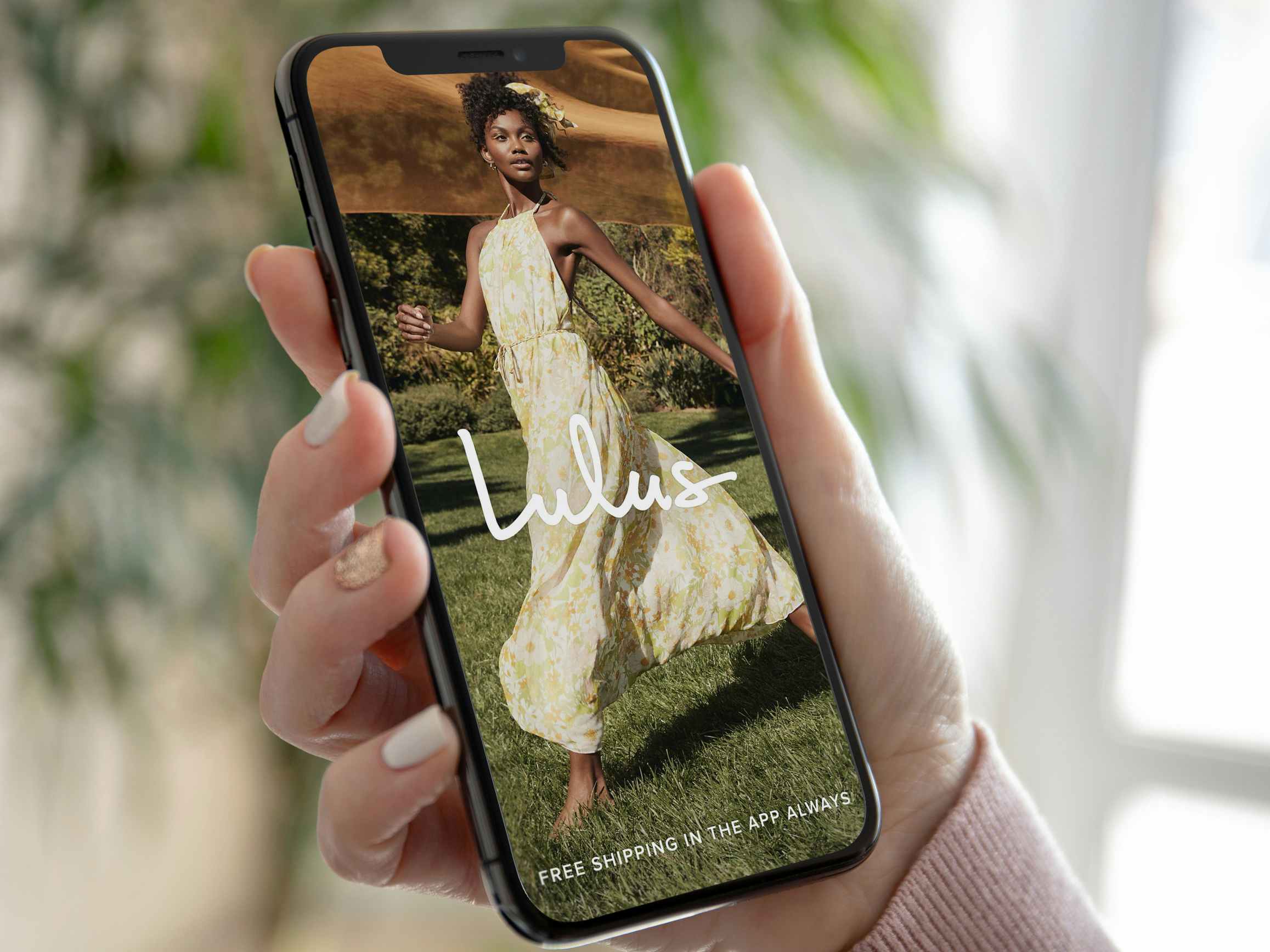 A person holding a cell phone displaying the Lulu's app information about free shipping when you use the app.