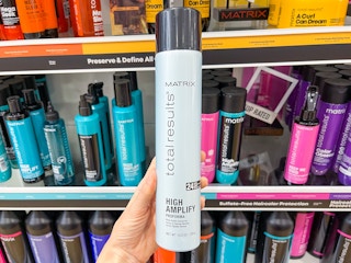 A Matrix hairspray held out in front of store shelf