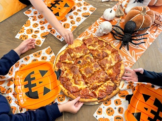 a group of hands grabbing at a pizza on table