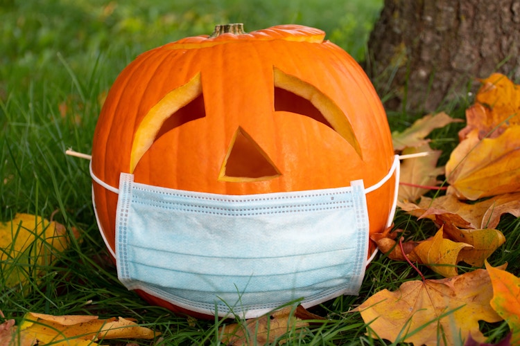 Carved pumpkin with a face mask on it.