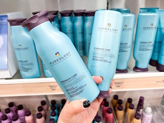 someone holding a pureology strength shampoo or conditioner