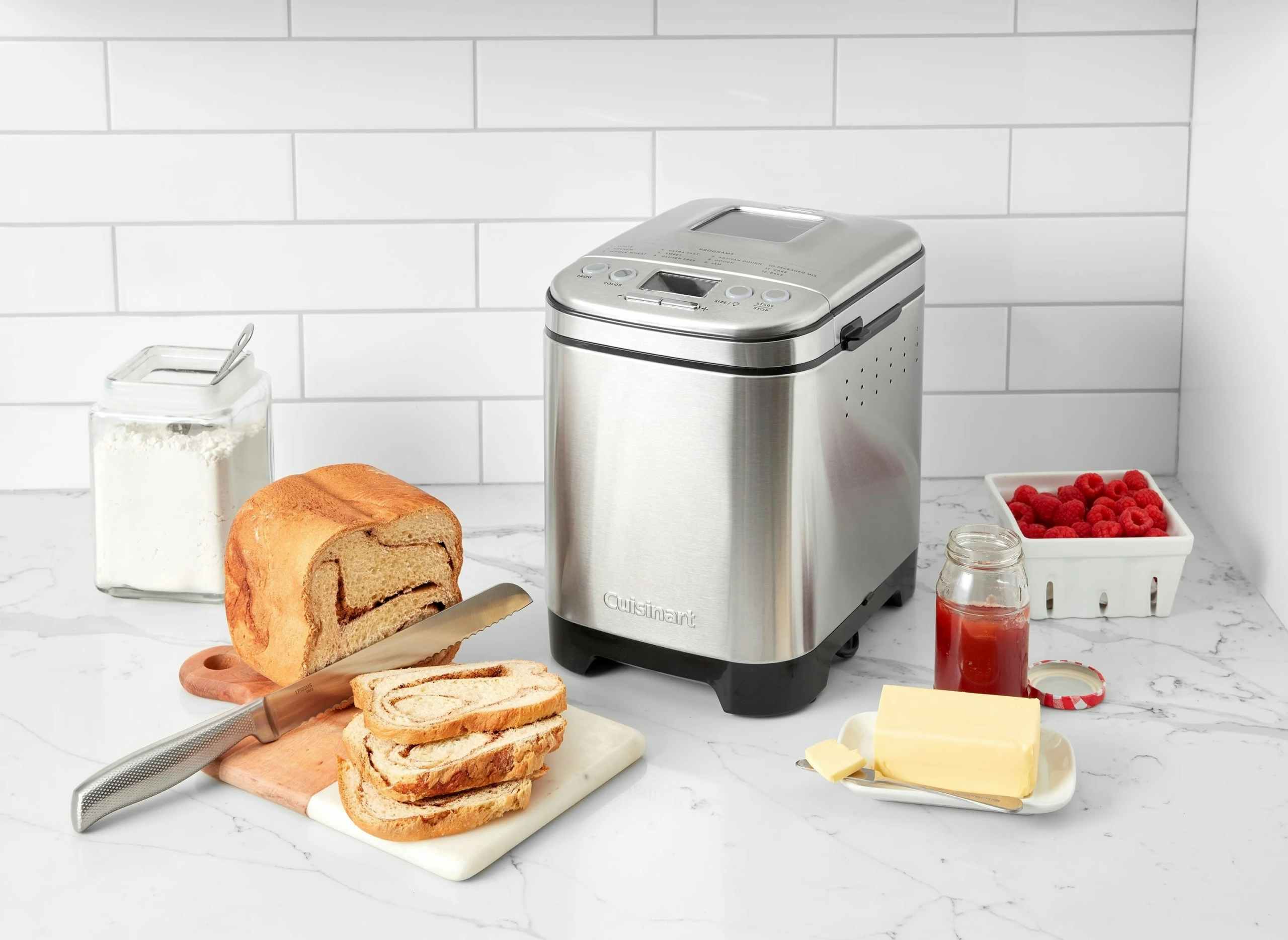 kitchen set up with a cuisinart bread maker, a loaf of bread being cut is next to it