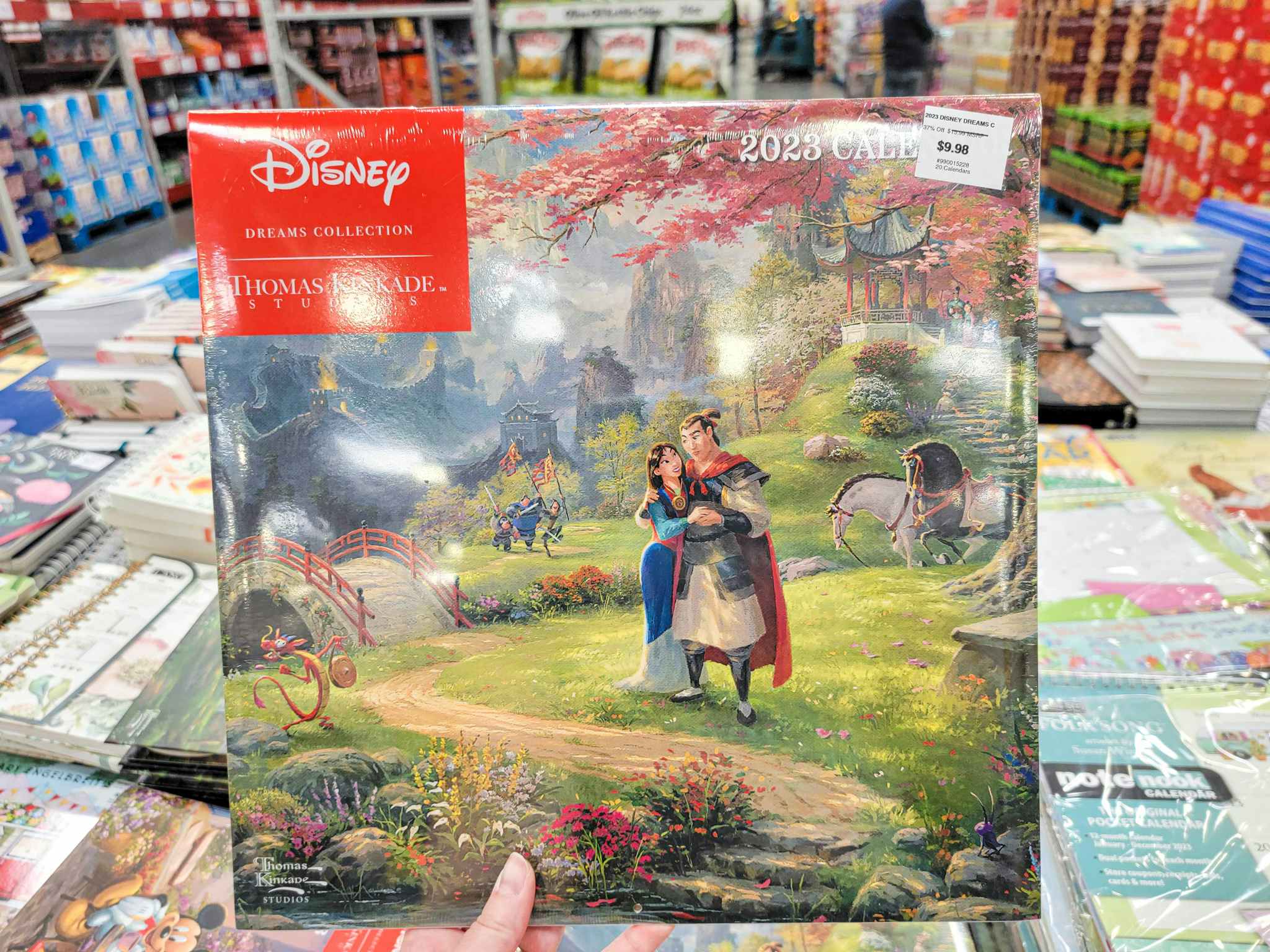 hand holding a 2023 disney thomas kinkade calendar