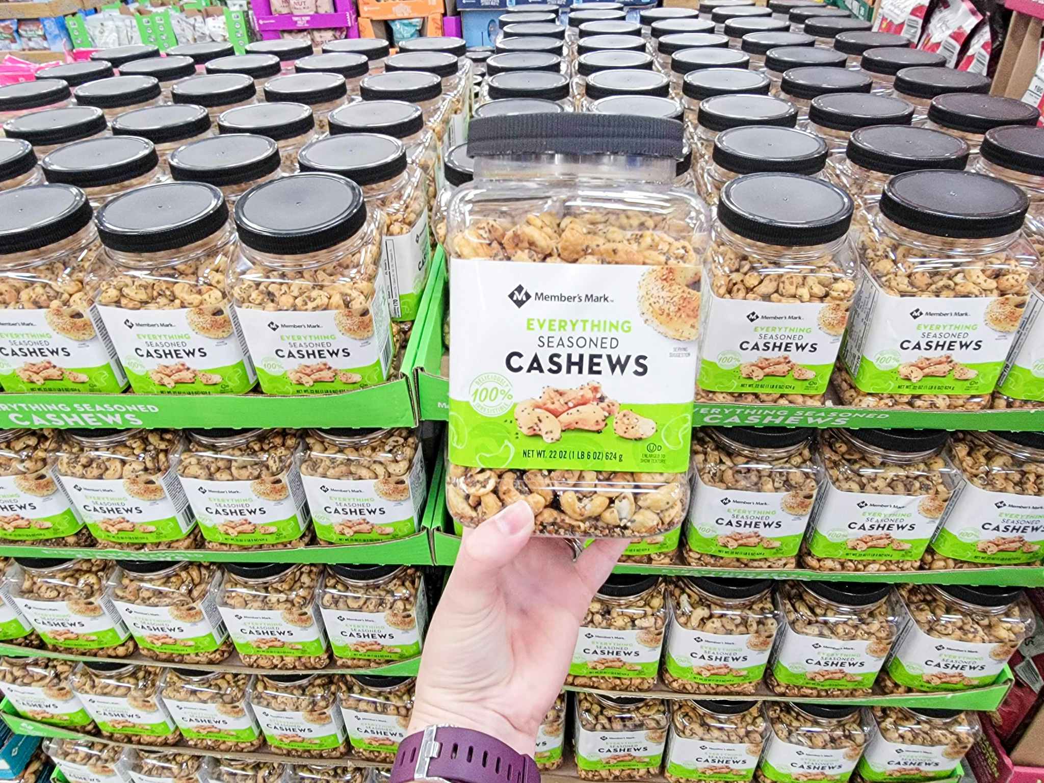 hand holding a container of everything seasoned cashews
