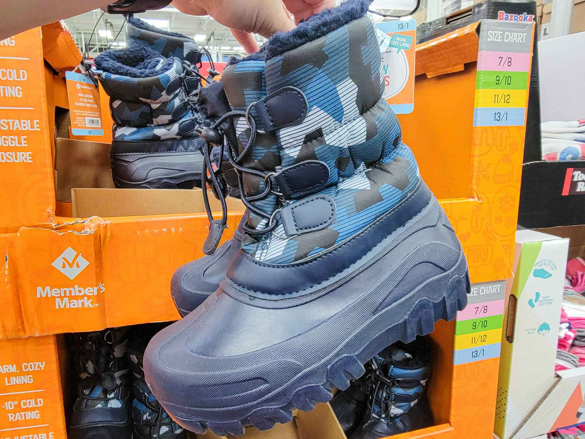 hand holding a pair of dark blue camo kids snow boots
