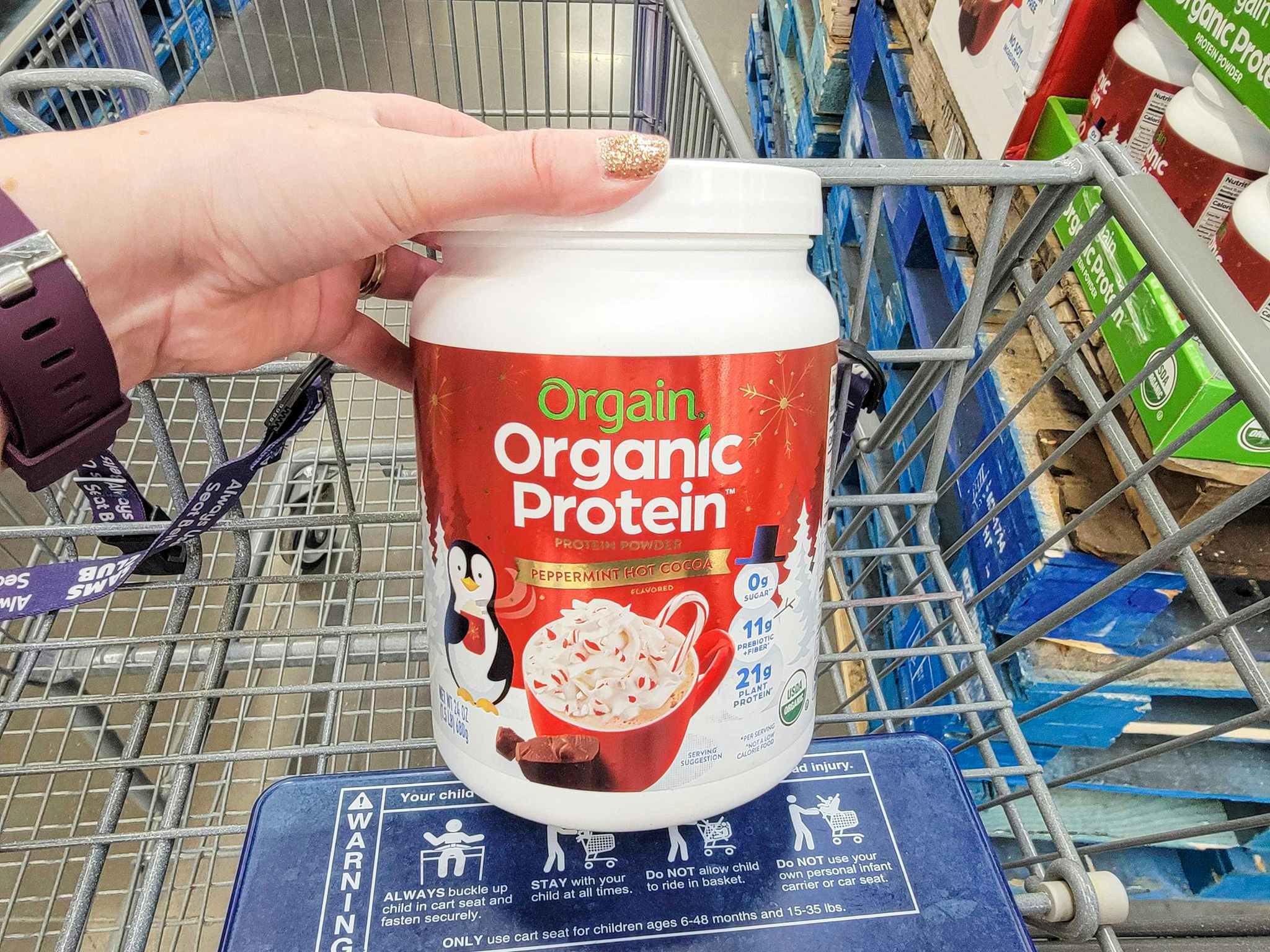 hand holding a bottle of peppermint hot cocoa protein powder in a cart