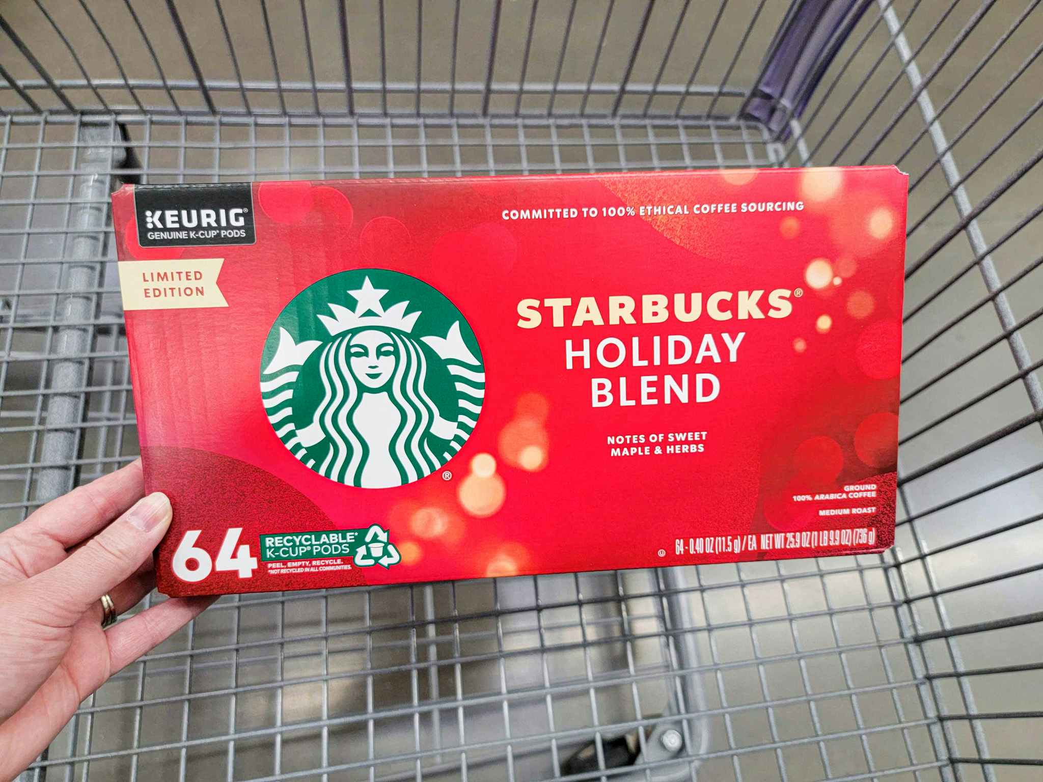 hand holding a box of starbucks holiday blend kcups in a cart