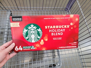 hand holding a box of starbucks holiday blend kcups in a cart