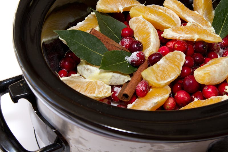 a slow cooker filled with fruit and cranberries.