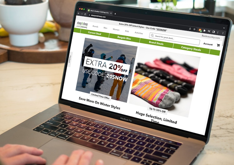 A person using a laptop displaying the Steep & Cheap website homepage