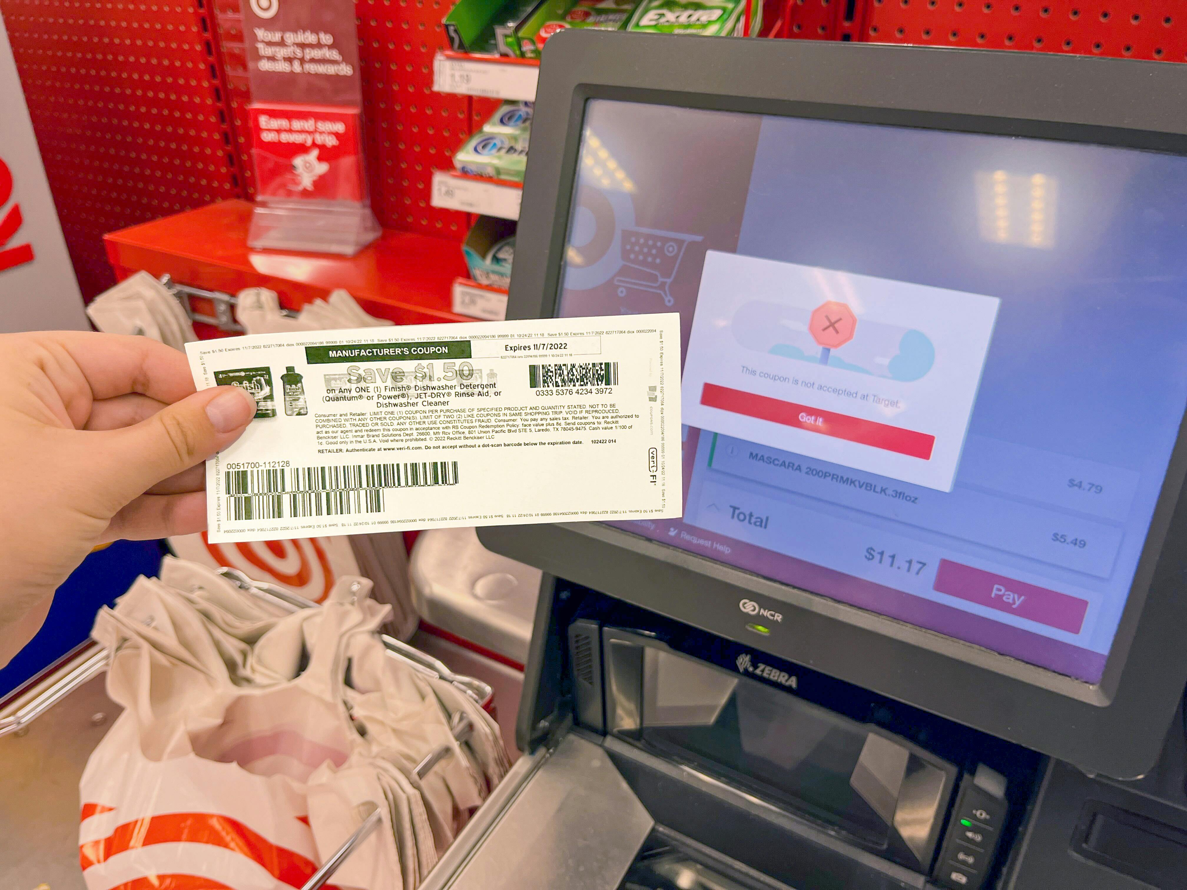 person holding manufacturer's coupon that won't work at target self check-out