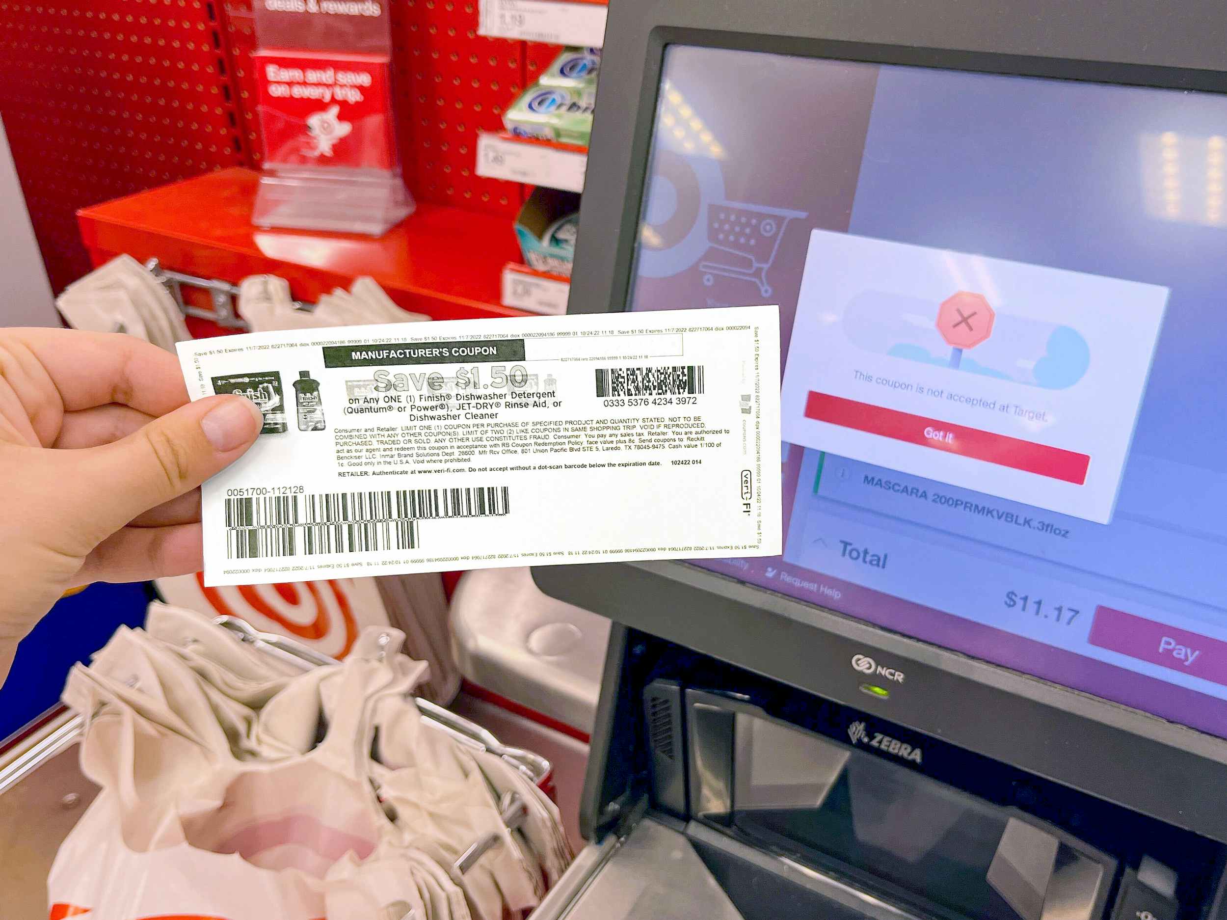 person holding up a rejected manufacturers coupon next to a target checkout screen