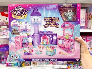 A person holding up a Magic Mixies Mixlings Castle Playset in Target.