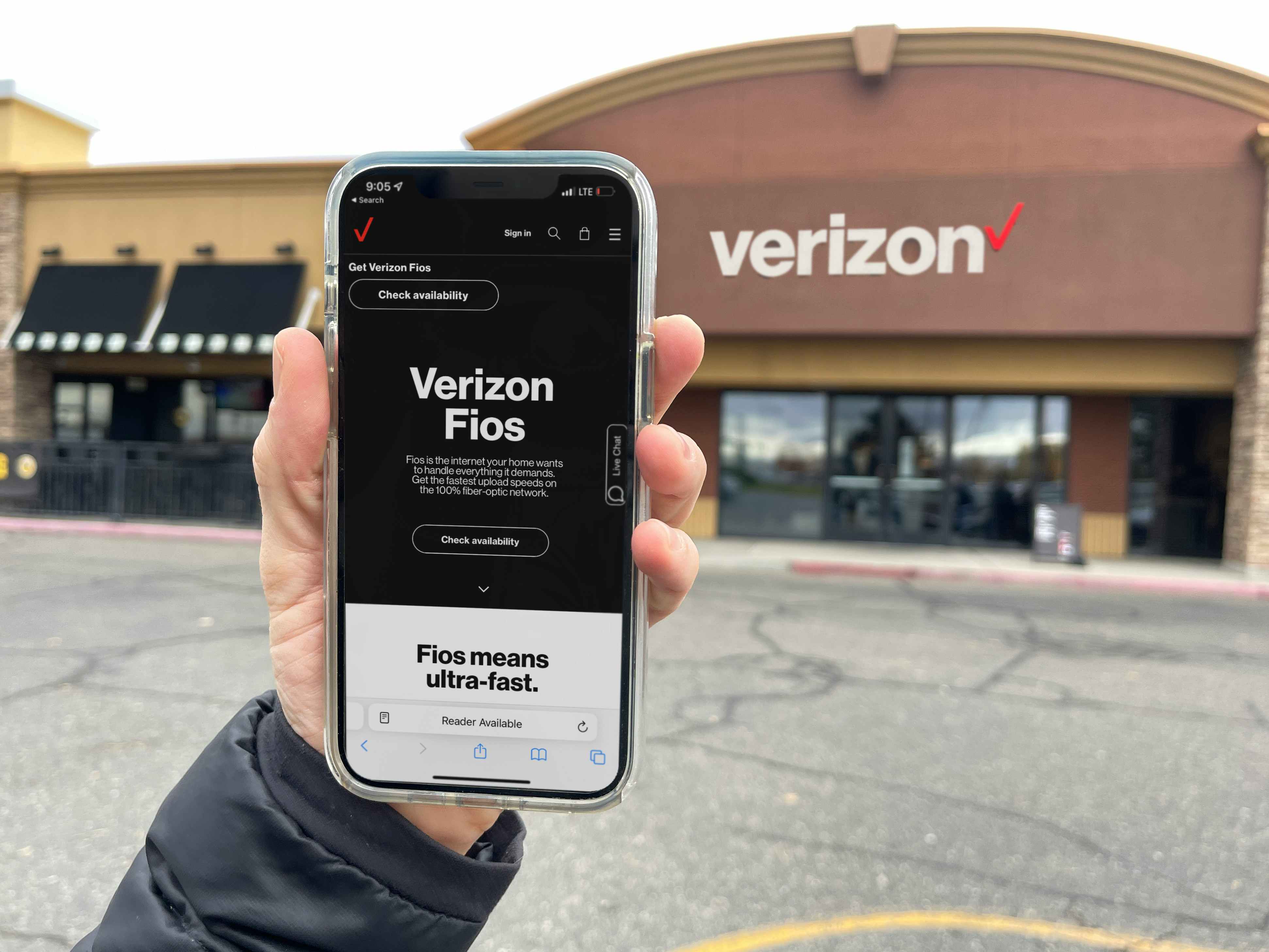 a hand holding a cellphone in front of verizon with verizon app fios on screen 
