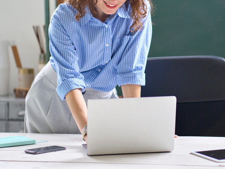 teacher in classroom working on laptop