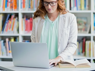 teacher working on laptop in library