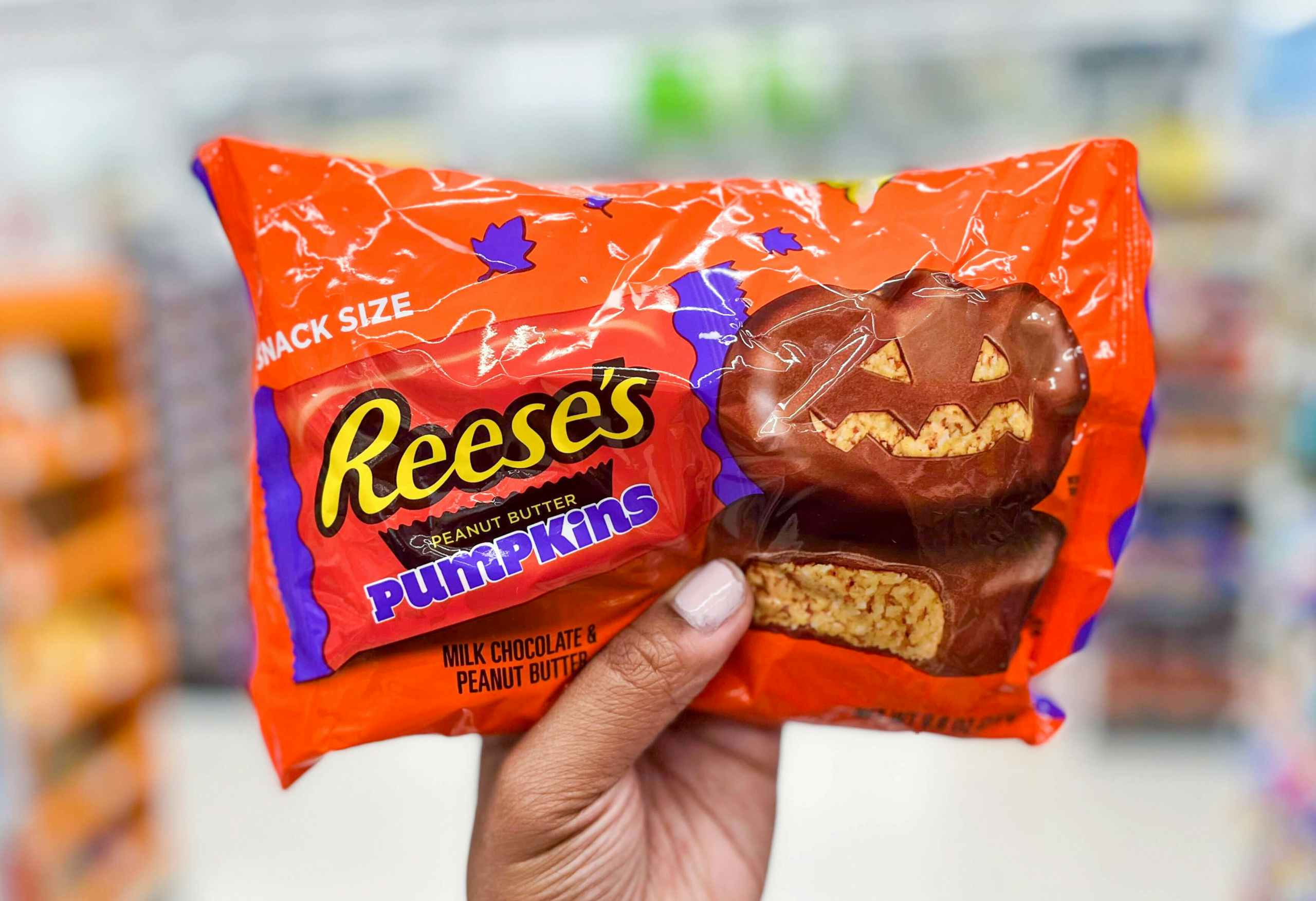 hand holding bag of Reese's peanut butter pumpkin chocolate candy in aisle