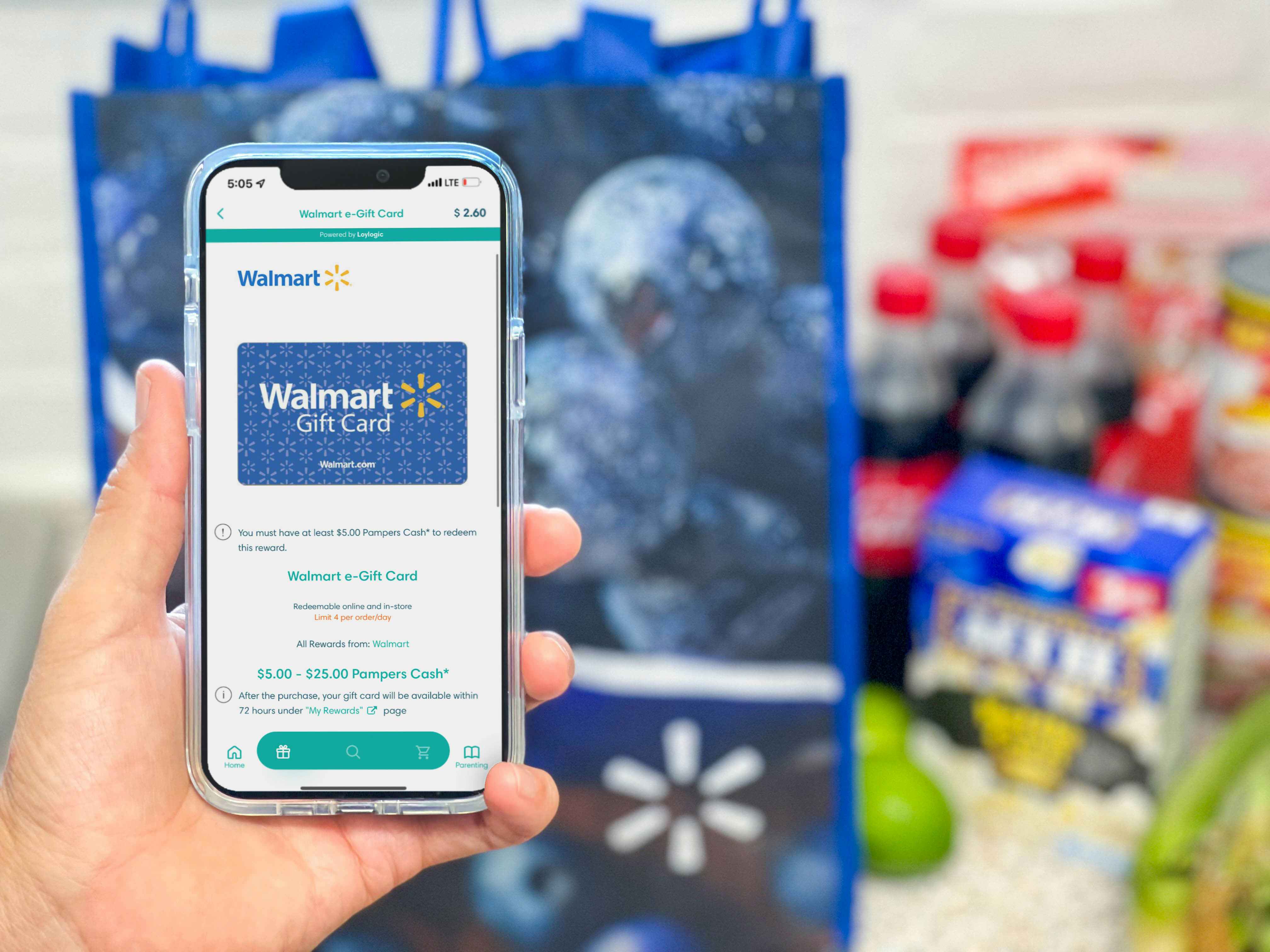 a hand holding a cellphone with pampers rewards app on screen in front of walmart groceries and bag