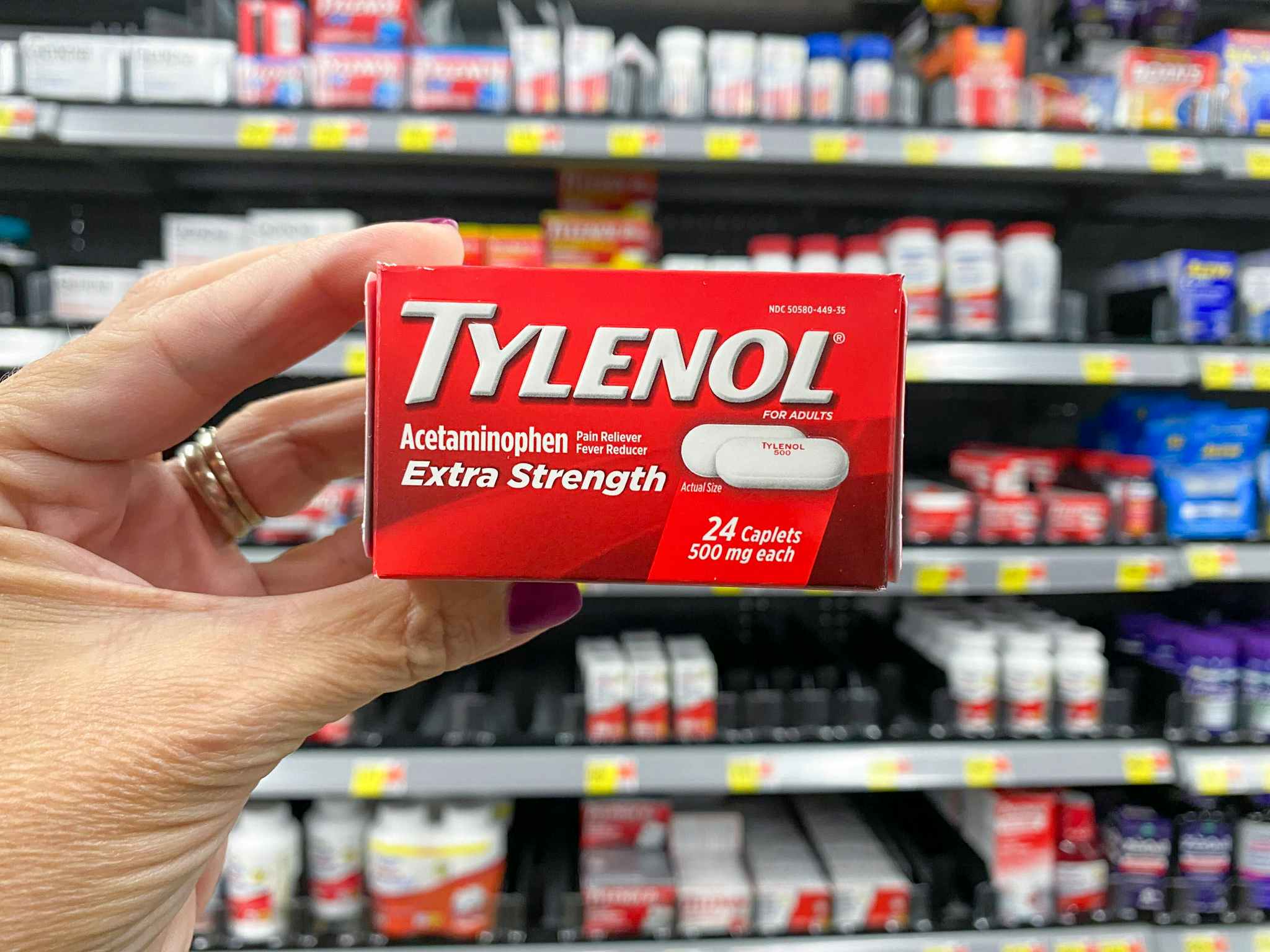 Someone holding up a box of Tylenol in a store