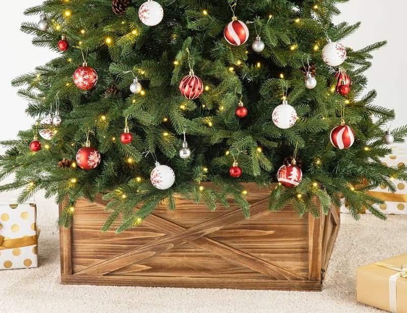 A Christmas tree set up with a St Ives Solid Wood Tree Collar on a carpeted floor