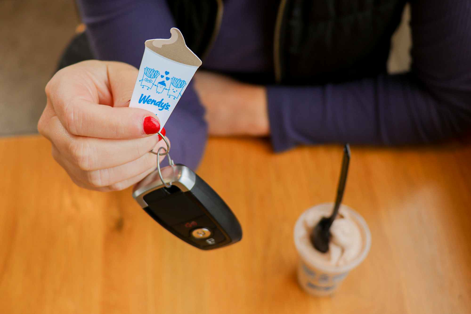 a person holding up a wendys frosty key tag