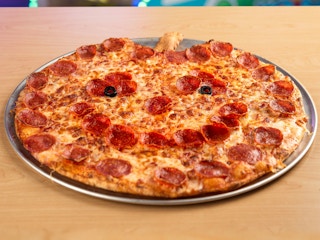 A pumpkin-shaped pizza from Chuck-E-Cheese served on a table.