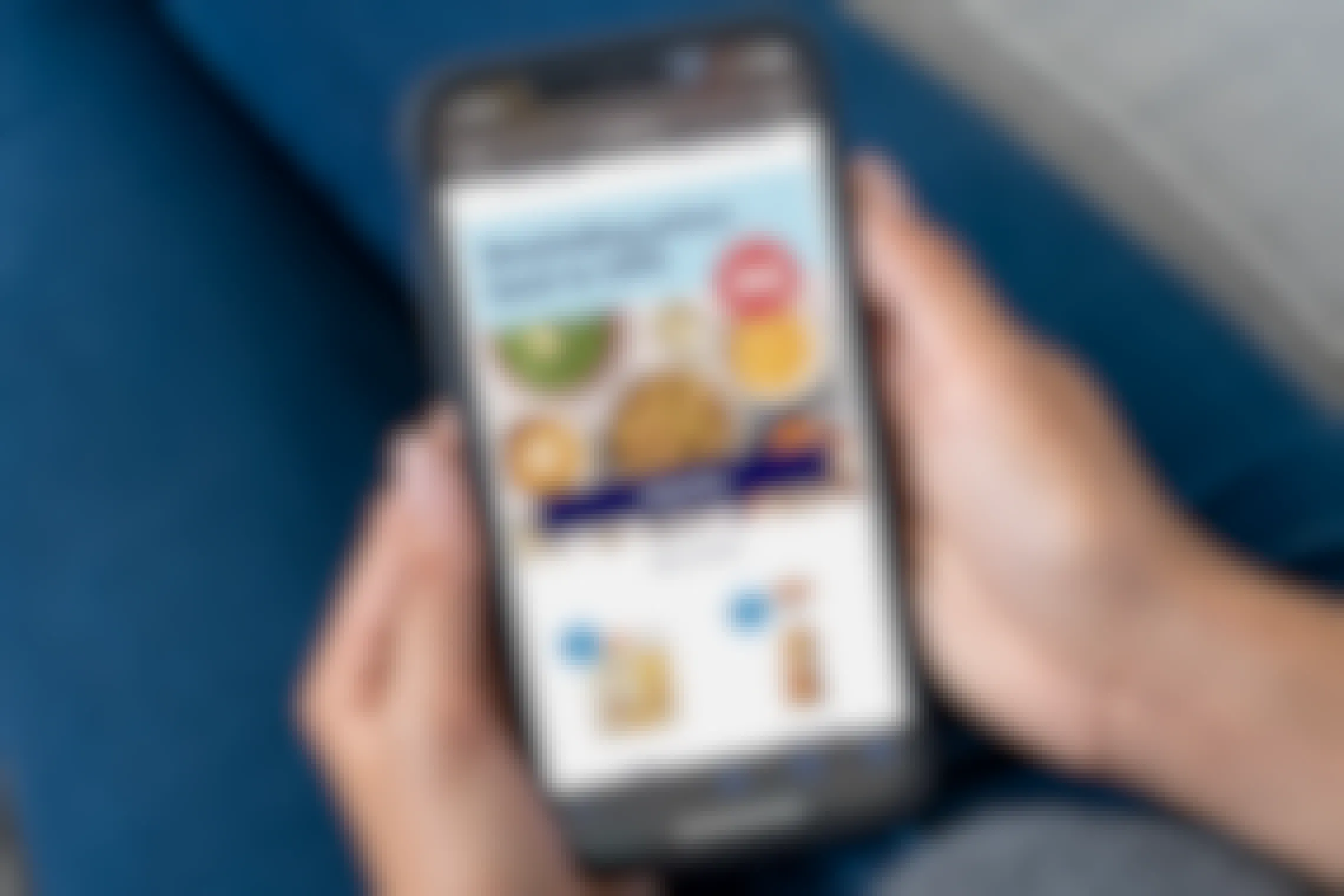 A person holding a cell phone displaying the ALDI website's graphic advertising their Thanksgiving Price Rewind offer program