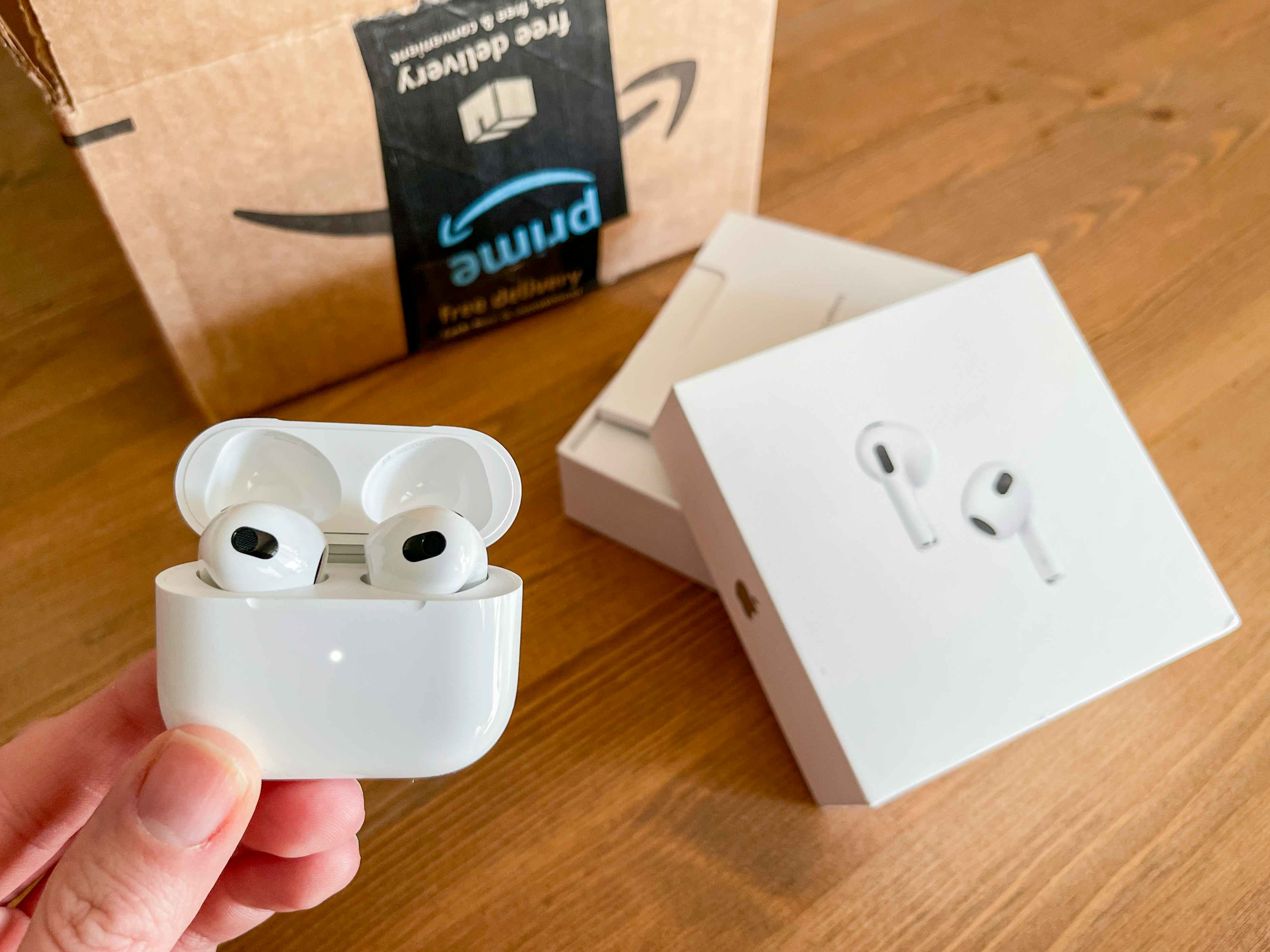 apple air pod pro being held next to amazon box