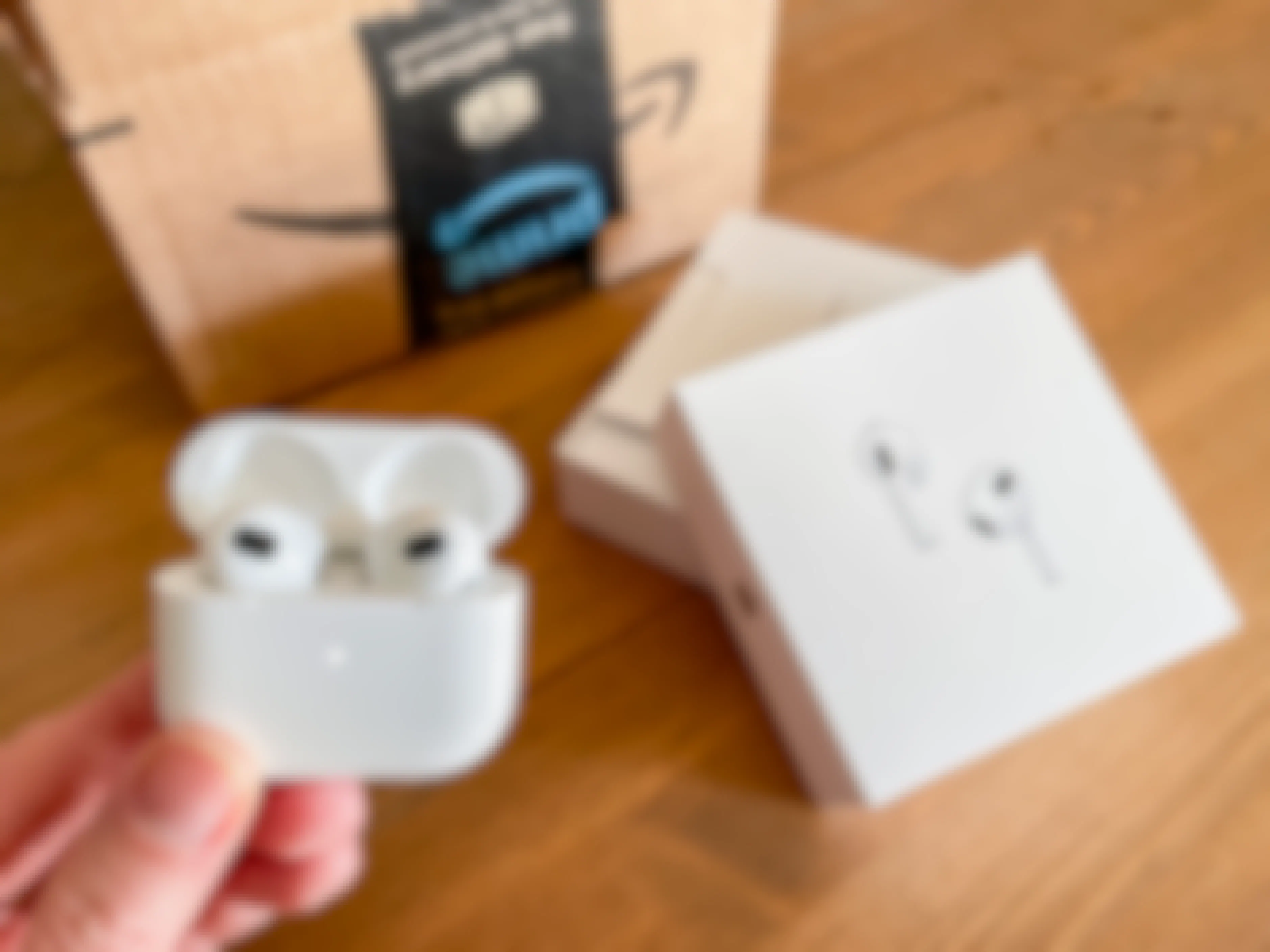 apple air pod pro being held next to amazon box