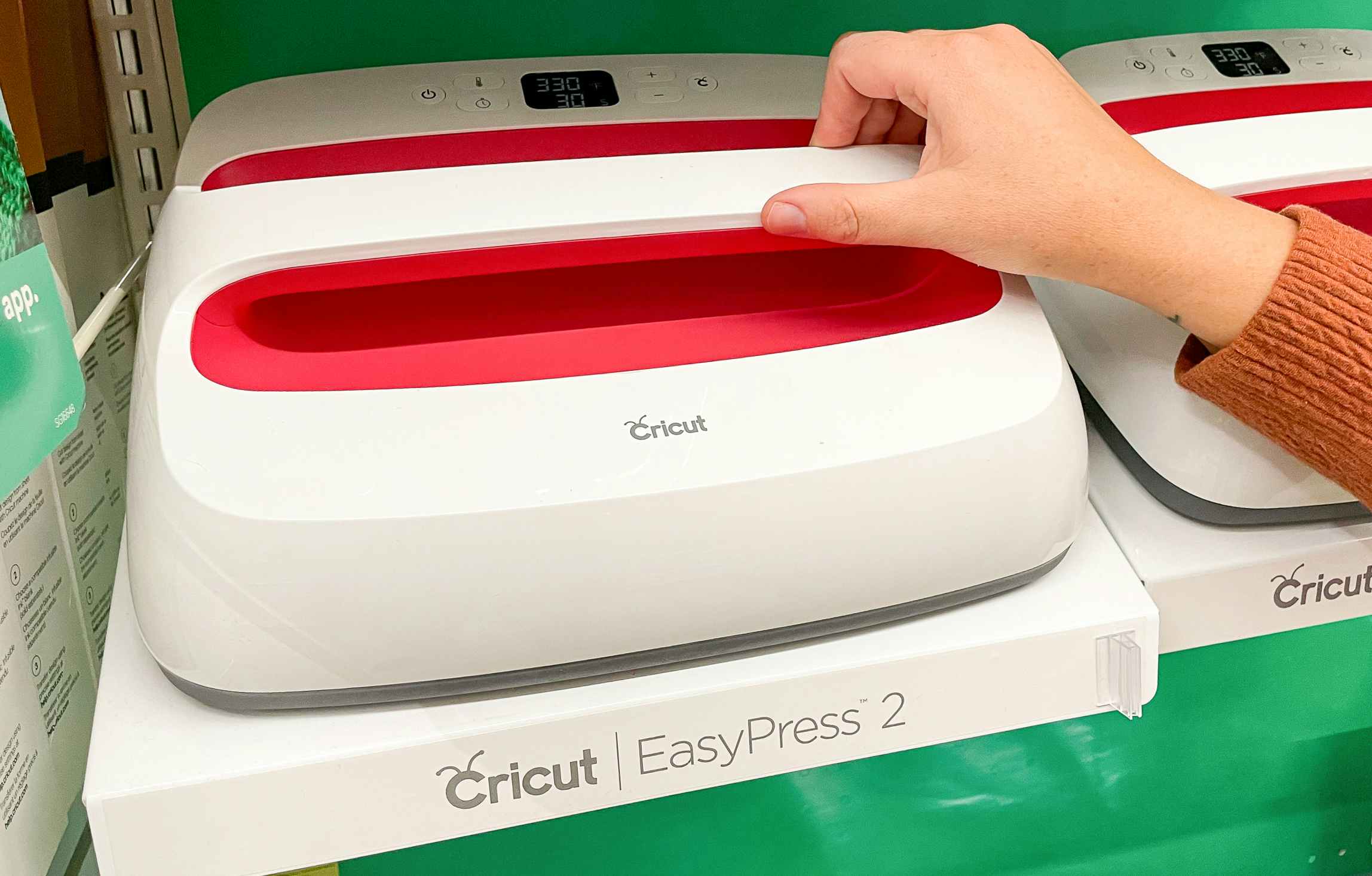 hand grabbing a cricut easy press 2 machine on a shelf