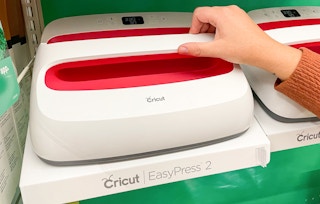 hand grabbing a cricut easy press 2 machine on a shelf