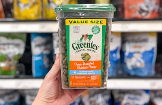 hand holding a large container of feline greenies cat dental treats