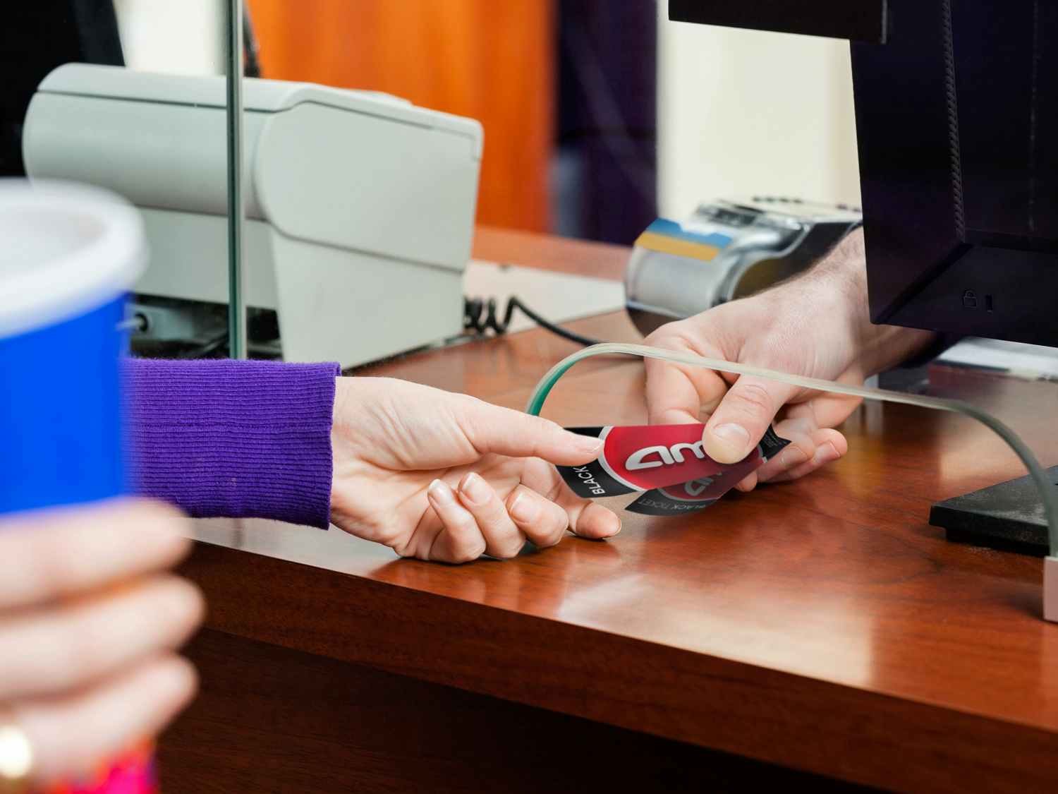 person receiving purchased movie tickets at amc theatre counter