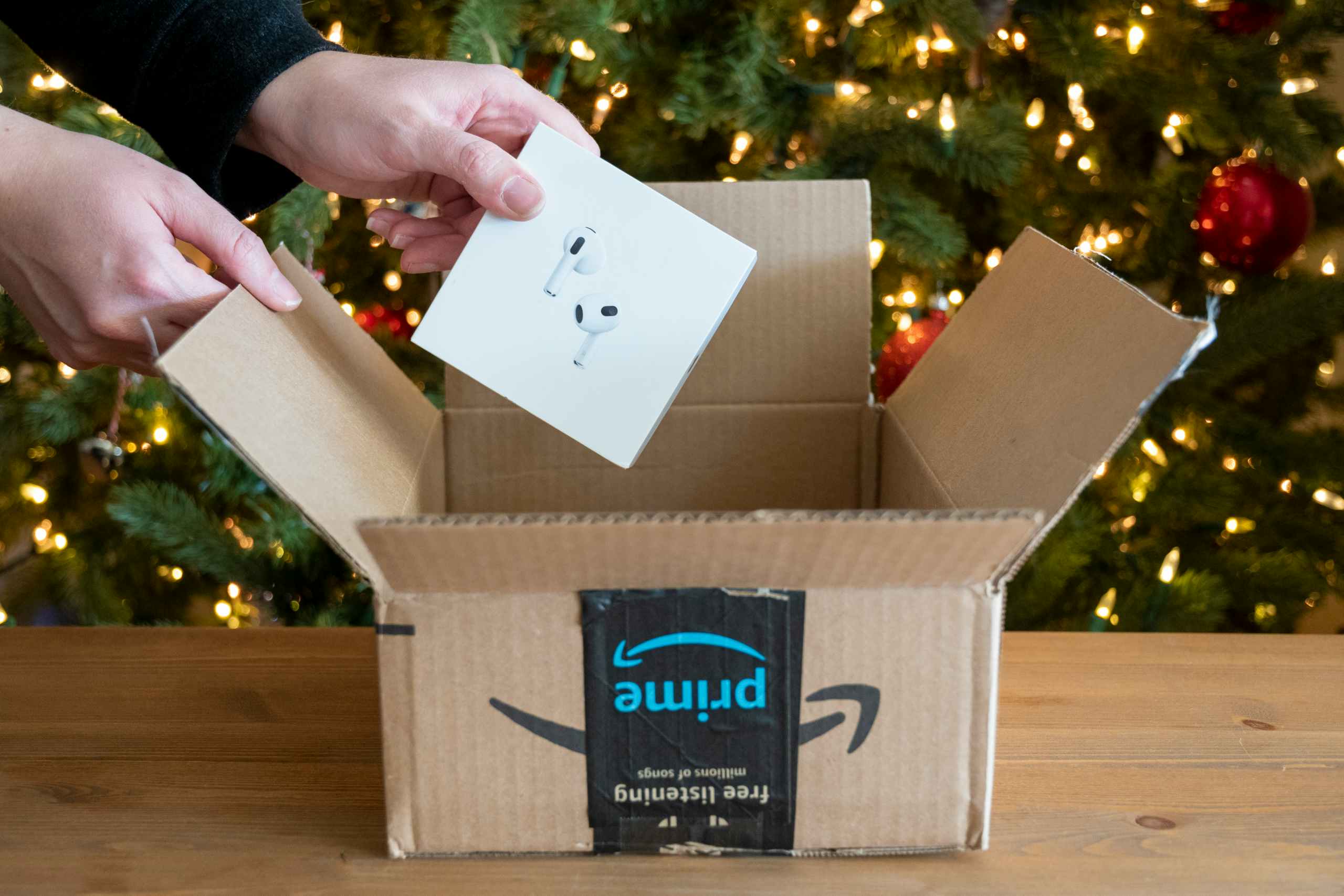 Apple Airpods pro with an amazon box in front of a Christmas tree.